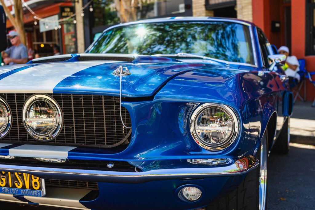 Sports Cars enthusiasts admire a blue Ford Mustang with white stripes, close-up view showcasing sleek design