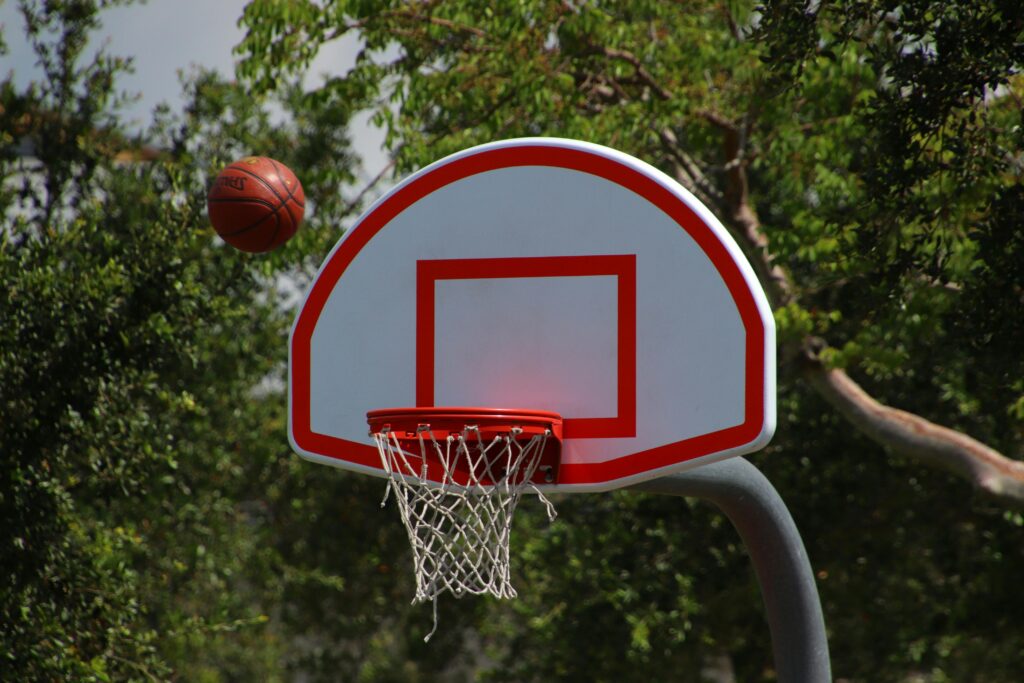 Basketball ball teeters on the edge of the hoop, poised for a score