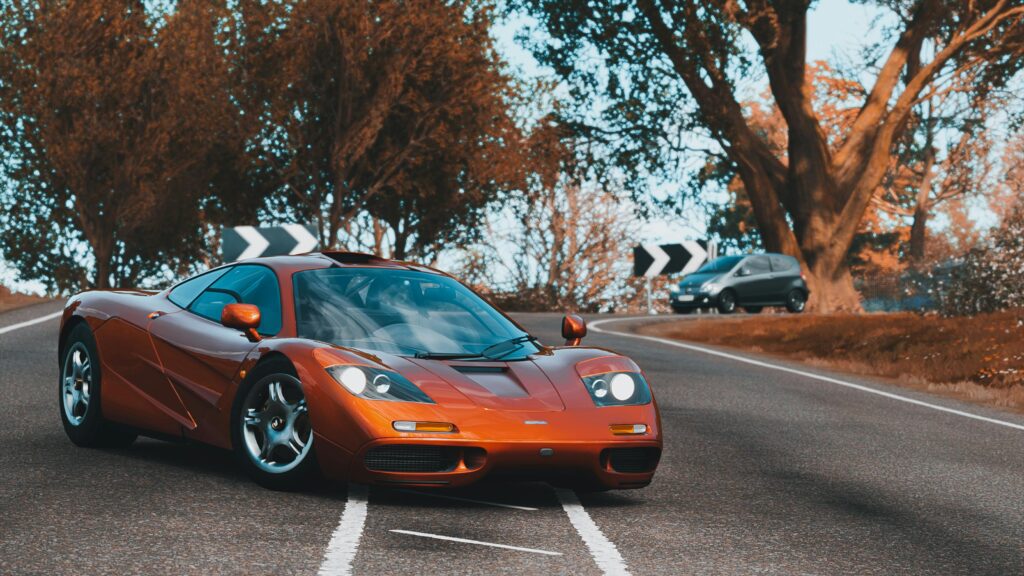 Sports Car enthusiasts admire a rare McLaren F1 LM parked on the road, showcasing its sleek design