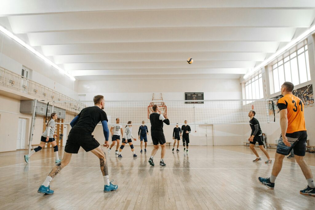 Volleyball players leaping to spike the ball during a competitive match, showcasing teamwork and athleticism.